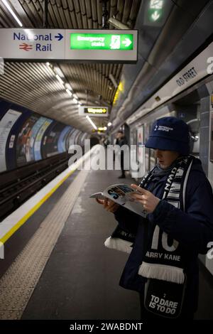 Young Spurs football fan with his match day programme travelling back home using the London Underground, England, United Kingdom Stock Photo