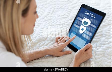 Blonde woman using chatbot on digital tablet, home interior Stock Photo