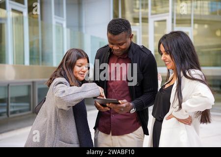 Multi-ethnic casual business people using a digital tablet in an outdoor meeting Stock Photo