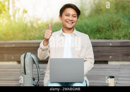 Smiling chinese guy independent contractor working at park Stock Photo