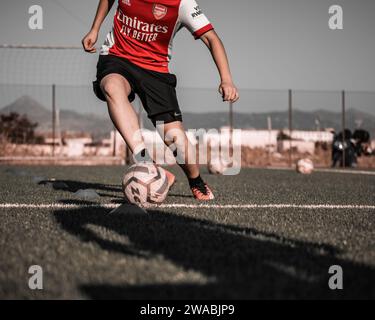 Silhouettes of two soccer players training on field with footballs and cones during sunset. Stock Photo