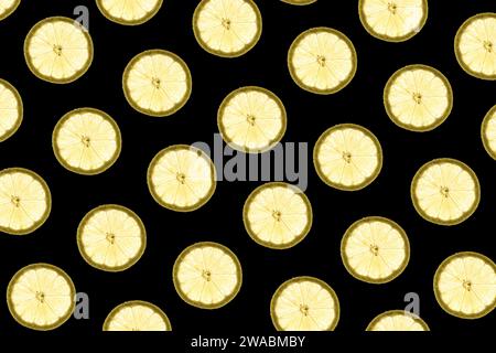Pattern made of backlit lemon slices on black background Stock Photo