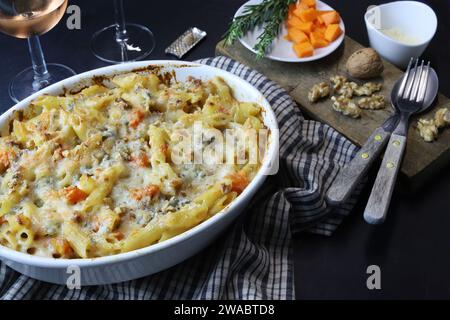 Homemade pasta with pumpkin, gorgonzola and walnuts in a white tray. Italian food concept. Overhead view. Italian cuisine. Stock Photo