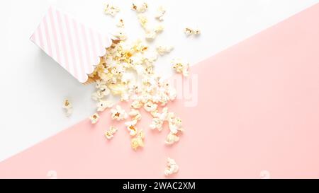 A striped bucket of popcorn on white and pink background, top view and copy space. Stock Photo