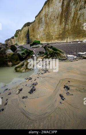 Low tide with sand and rocks on a beach with chalk cliffs Stock Photo
