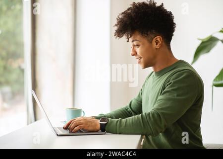 Side view young black man working at cozy cafe Stock Photo