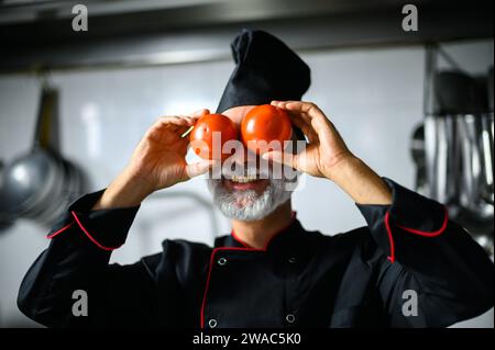Funny chef covering his eyes with tomatoes Stock Photo