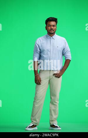 A man in a blue shirt, on a green background, in full height Stock Photo