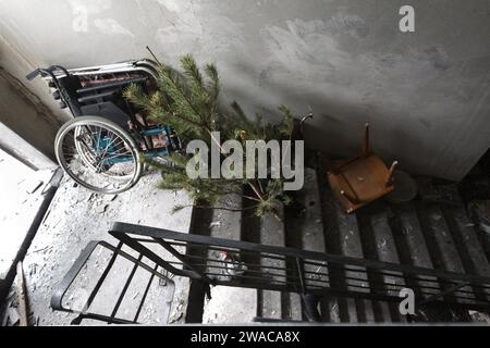 Non Exclusive: KYIV, UKRAINE - JANUARY 3, 2024 - A wheelchair and a spruce tree are seen at the top of a flight of stairs in a residential building in Stock Photo