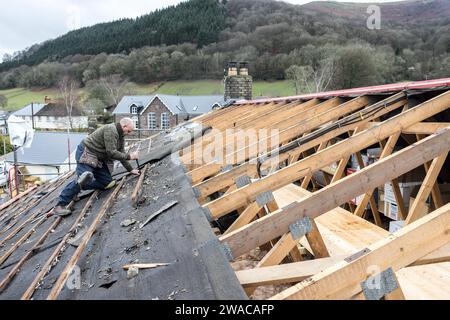 Roofer removing old batons and felt from pitched roof on house, Llanfoist, Wales, UK Stock Photo