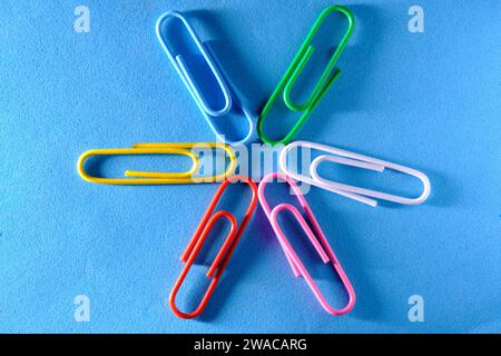 Multi colored paper clips are folded in shape star blue background Stock Photo