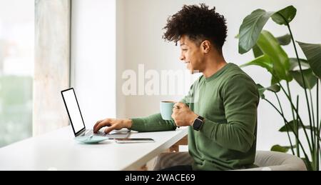Positive cool african american guy using laptop at cafe Stock Photo