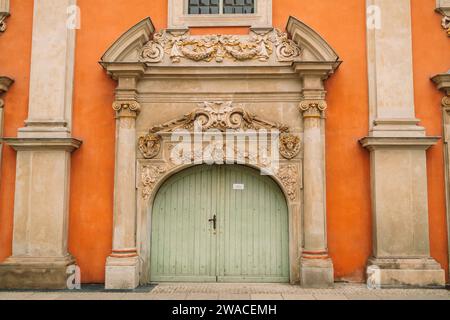 Wooden double barn door with rounded corners, stone wall. Orange wall with antique decor of columns Stock Photo