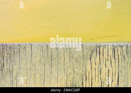 Close-up of a cracked & weathered wooden wall & plastered concrete wall painted in bright and light yellow. Abstract textured background, copy space. Stock Photo