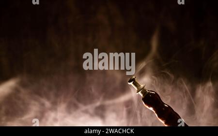 Modern hookah, shisha on a smoky black background with neon lighting and smoke. Place for your text Stock Photo