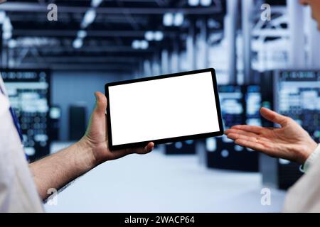 Senior teamworking colleagues in high tech workplace using mock up tablet to set up configuration management tools that enable automatic failover and load balancing, preventing server parts failure Stock Photo