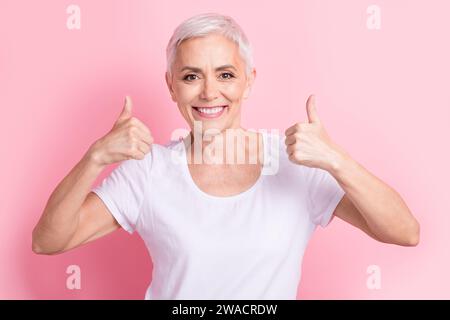 Photo portrait of lovely senior lady showing double thumb up wear trendy white garment isolated on pink color background Stock Photo