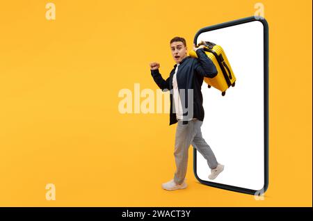 Motivated young guy traveler with suitcase step out of phone Stock Photo