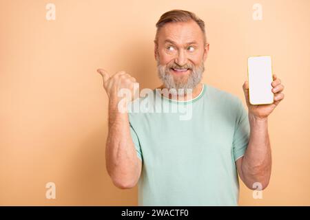 Photo of cheerful nice senior man wear stylish clothes presenting empty space isolated on beige color background Stock Photo