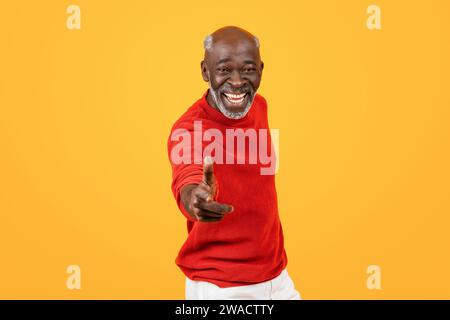 Welcoming senior Black man with a white beard, reaching out for a handshake and smiling widely Stock Photo