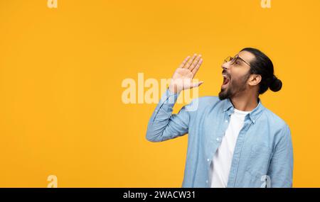 An animated man with a beard and glasses enthusiastically shouts or calls out to someone Stock Photo