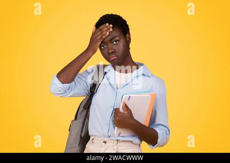 Black sad lady student with books, visibly tired and sweating, depicts exhaustion Stock Photo