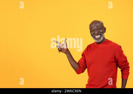Happy senior Black man with a white beard, pointing to the side with a big smile Stock Photo