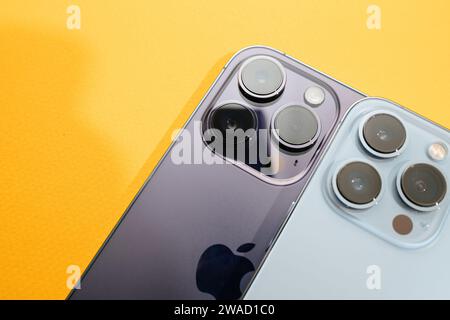 Paris, France - Sep 29, 2022: A close-up view of two luxury Apple iPhone models, 13 Pro and 14 Pro, placed side by side against a yellow background, highlighting their features Stock Photo