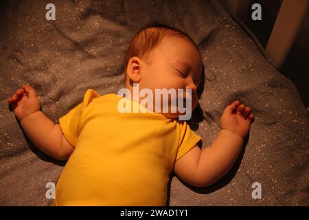 Cute newborn baby sleeping in crib at night, top view Stock Photo