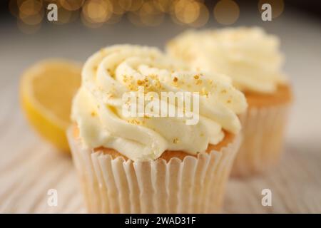 Tasty cupcake with cream, zest and lemon slice on black textured table ...