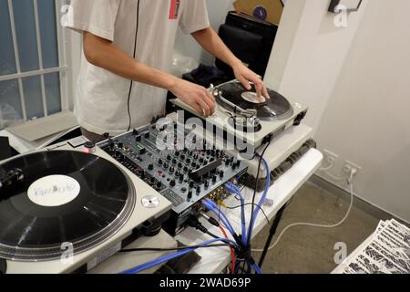 DJ working the decks, spinning vinyl at M2 art Gallery for a Graphic Art and Zine opening night event and party Stock Photo