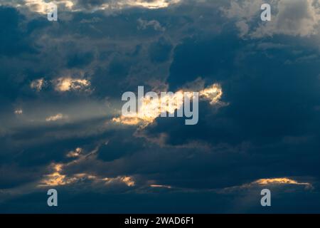 Sunlight shining through dark clouds at sunset Stock Photo