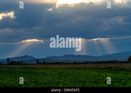 Sunlight shining through dark clouds at sunset Stock Photo