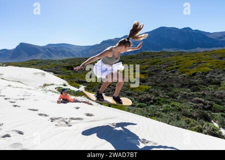 South Africa, Teenage girl (16-17) and boy (10-11) sand boarding in Walker Bay Nature Reserve Stock Photo