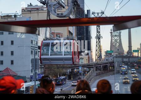 A tram leaves the Manhattan tram station for Roosevelt Island. Roosevelt Island, nestled in the East River between the boroughs of Manhattan and Queens in New York City, offers a unique blend of tranquility and urban living. Accessible by tram, subway, or bridge, this narrow island boasts a serene atmosphere distinct from the bustling city nearby. Home to a diverse community, it features a mix of residential complexes, parks, and historic landmarks like the renovated Blackwell House. Visitors and residents enjoy scenic waterfront views, tree-lined pathways perfect for strolls or bike rides, an Stock Photo