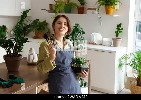 Female gardener with florarium and tools in kitchen Stock Photo