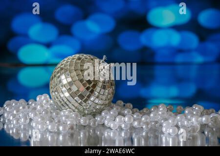 A  Christmas Tree bauble in the form of a Glitterball, photographed with a white beaded necklace, against a blue background Stock Photo