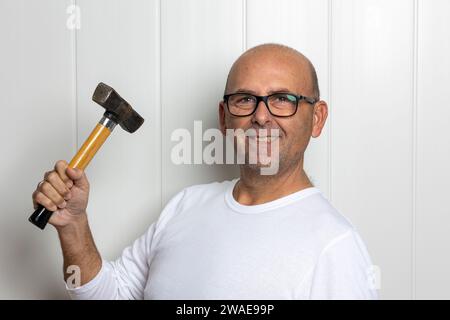 A middle-aged male holding a hammer and smiling while posing Stock Photo
