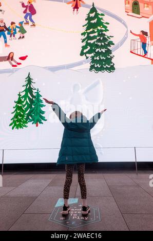 girl making snow angels in interactive display, the Now Building, London, UK Stock Photo
