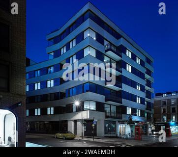 Corner elevation of building across intersection at dusk. Westbourne House, London, United Kingdom. Architect: Stiff + Trevillion Architects, 2015. Stock Photo