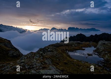 The valley of Sarca di Campiglio covered with clouds, the main range of Brenta Dolomites sticking out of the clouds, at sunrise. Stock Photo