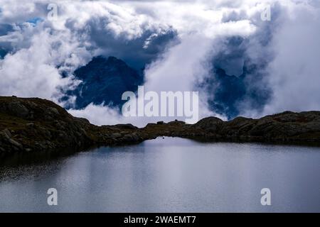 The main range of Brenta Dolomites, covered in clouds, seen from the lake Lago Nero. Stock Photo