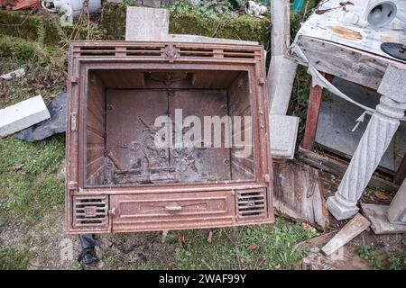 Fireplace with wood burning stove out of use and in a state of degradation, scrap. Antique objects. Stock Photo