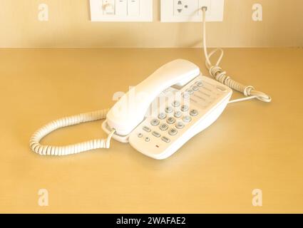 Old modern of telephone in hotel room near bed is served for guests in hotel room. Stock Photo