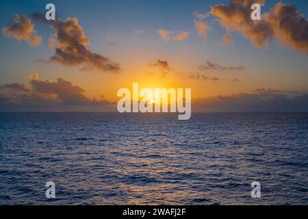 A beautiful sunset is captured over the crystal blue waters of the ocean on a clear day Stock Photo