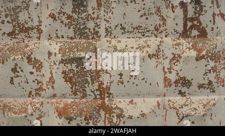 shabby concrete wall with square bumps and flaking paint as rough texture, cracked light paint on a surface of hard solid gray material as background Stock Photo