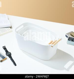 White universal plain plastic tray with wooden handle, on white and cream colored background. Stock Photo