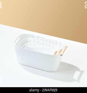 White universal plain plastic tray with wooden handle, on white and cream colored background. Stock Photo