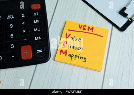 Concept of VSM - Value Stream Mapping write on sticky notes isolated on Wooden Table. Stock Photo