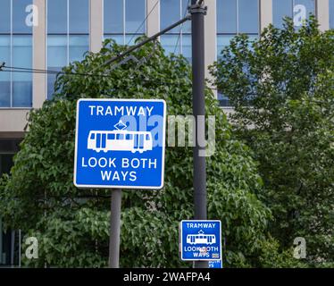 A UK street sign advising pedestrians to look both ways.at a tramway. A blue road sign advising of a tramway. Stock Photo